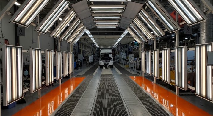 Automotive manufacturing light tunnel with bright inspection lighting and orange epoxy floor, highlighting precision vehicle inspection, high-performance industrial flooring, and durable epoxy coatings for factory and assembly line environments.