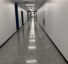Commercial hallway with seamless gray epoxy flooring, featuring a polished, slip-resistant surface ideal for hospitals, offices, schools, and high-traffic institutional interiors.