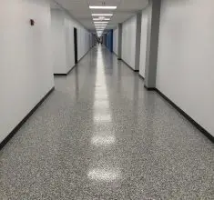 Commercial hallway with seamless gray epoxy flooring, featuring a polished, slip-resistant surface ideal for hospitals, offices, schools, and high-traffic institutional interiors.