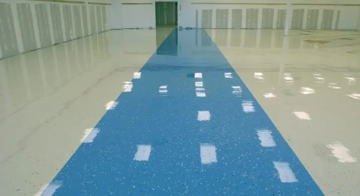 Commercial epoxy flooring installation with a glossy blue walkway and light-colored epoxy surface, showing a seamless, durable, slip-resistant floor finish ideal for warehouses, retail spaces, and industrial interiors.