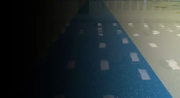 Commercial epoxy flooring with a blue center lane and high-gloss finish, highlighting a seamless, durable, and slip-resistant surface ideal for warehouses, gyms, industrial facilities, and high-traffic commercial interiors.