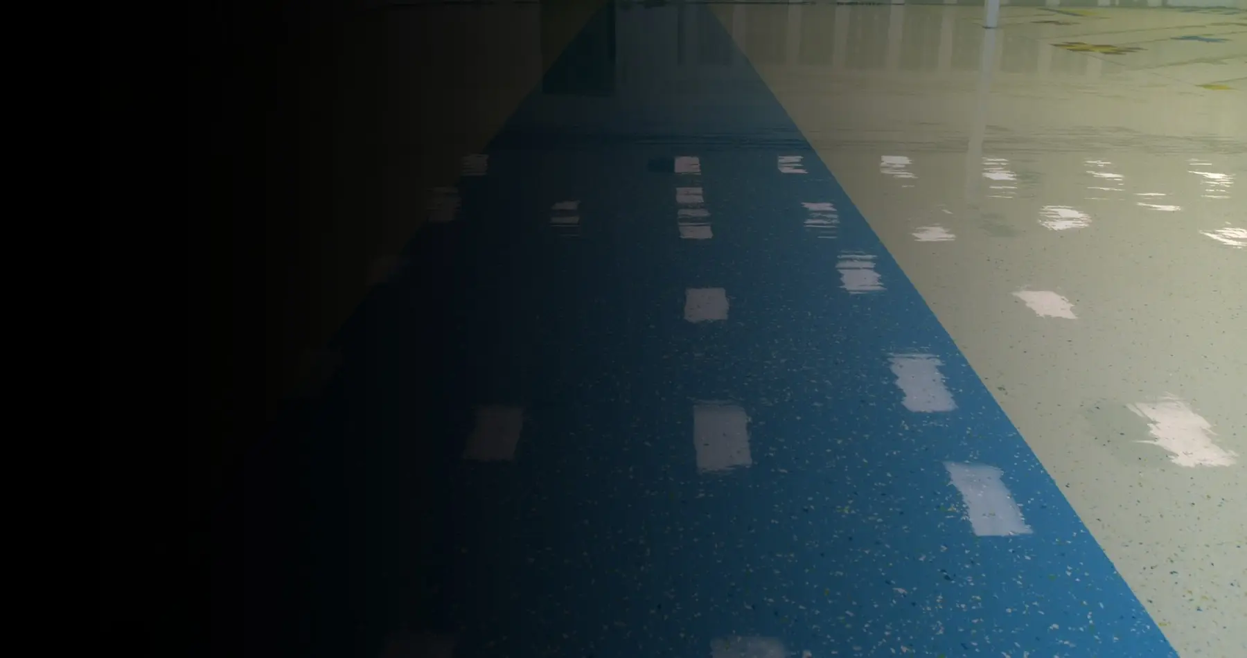 Commercial epoxy flooring with a blue center lane and high-gloss finish, highlighting a seamless, durable, and slip-resistant surface ideal for warehouses, gyms, industrial facilities, and high-traffic commercial interiors.